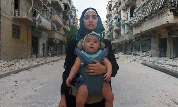 Waad Al-Kateab cargando a su hija Sama en medio de las calles destruidas en Siria.